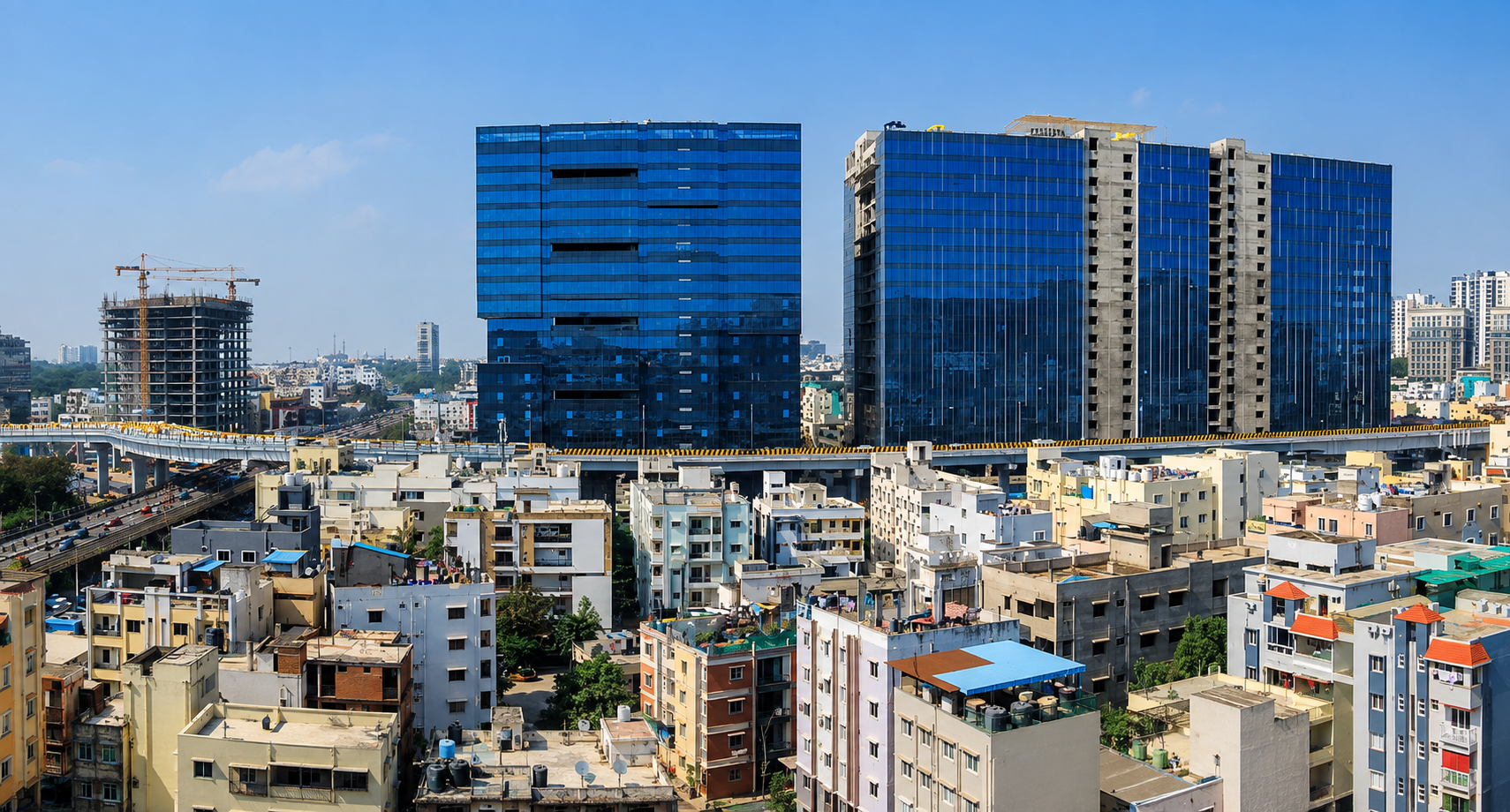 Aerial view of Hyderabad's office towers and metro rail corridor bordering a dense residential neighbourhood