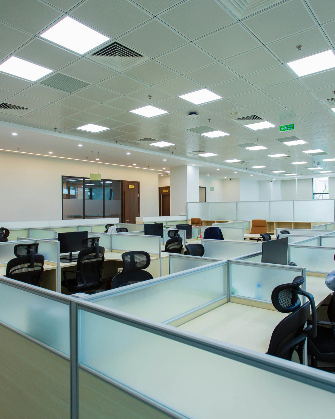 Open-plan managed office workstations with glass-partitioned cabins and ceiling lighting